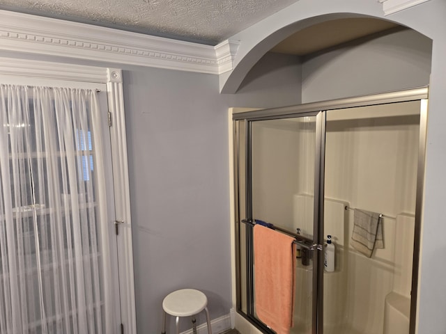 bathroom featuring crown molding, a textured ceiling, and a shower with shower door