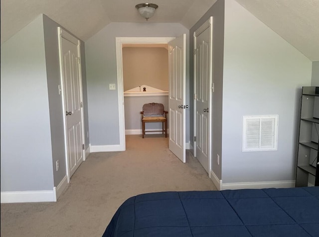 unfurnished bedroom with vaulted ceiling, light carpet, baseboards, and visible vents