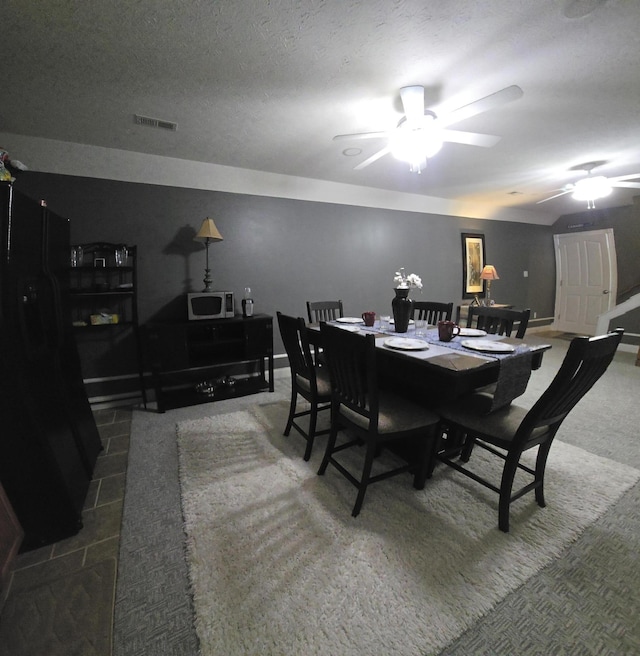 carpeted dining room featuring a ceiling fan, baseboards, and visible vents