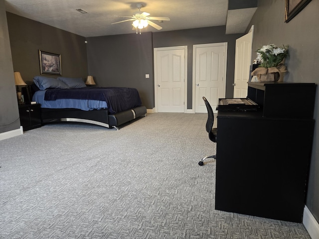 carpeted bedroom featuring visible vents, baseboards, a ceiling fan, and multiple closets