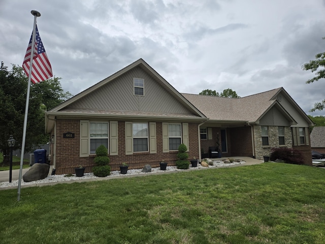 view of front of property featuring a front lawn, brick siding, and roof with shingles