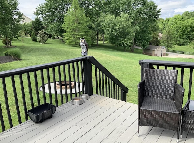 wooden deck with a storage shed, an outdoor structure, and a lawn
