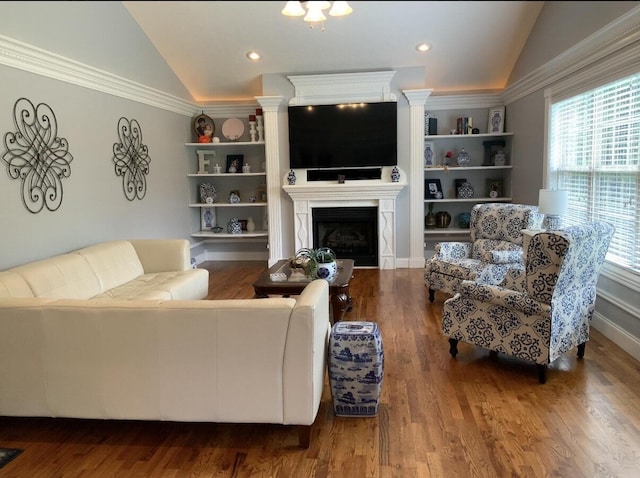 living area featuring vaulted ceiling, built in shelves, a fireplace, and wood finished floors