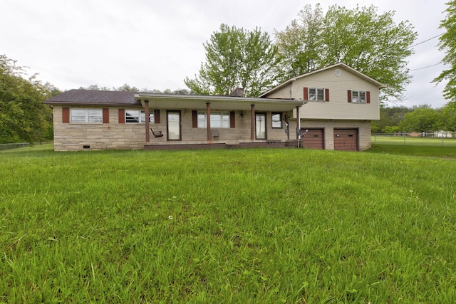 split level home featuring fence, an attached garage, stone siding, a front yard, and a chimney