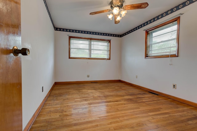 spare room with baseboards, light wood-type flooring, a ceiling fan, and visible vents