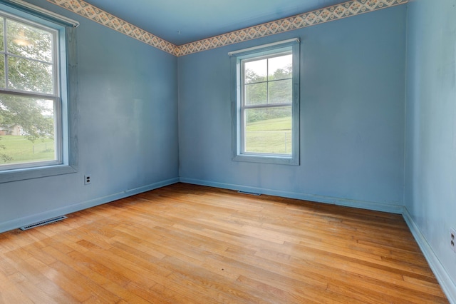 empty room with visible vents, wood finished floors, and baseboards