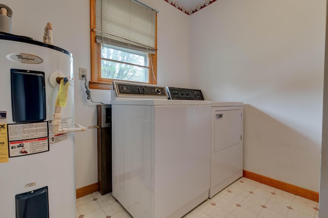 clothes washing area featuring baseboards, separate washer and dryer, laundry area, and electric water heater