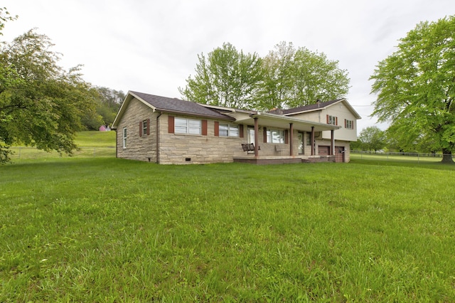back of property with stone siding, a yard, and fence
