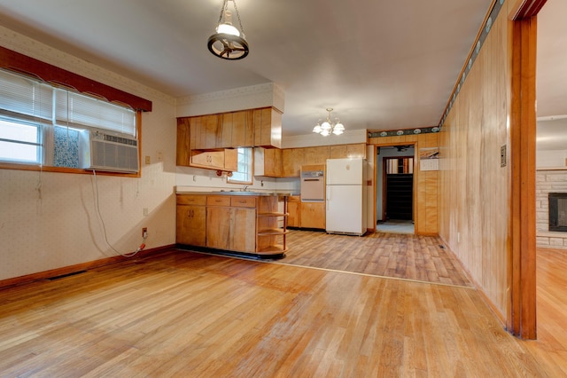 kitchen featuring a wealth of natural light, white appliances, a chandelier, brown cabinets, and light wood-type flooring