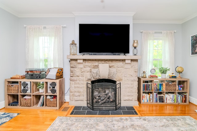 living area featuring wood finished floors, ornamental molding, a fireplace, and baseboards