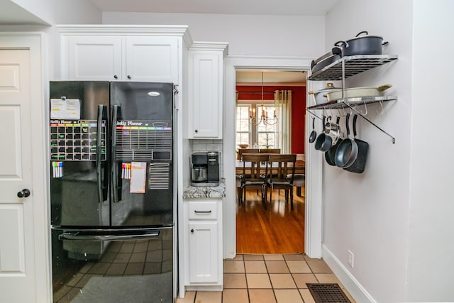 kitchen with freestanding refrigerator, a chandelier, white cabinetry, light tile patterned floors, and baseboards