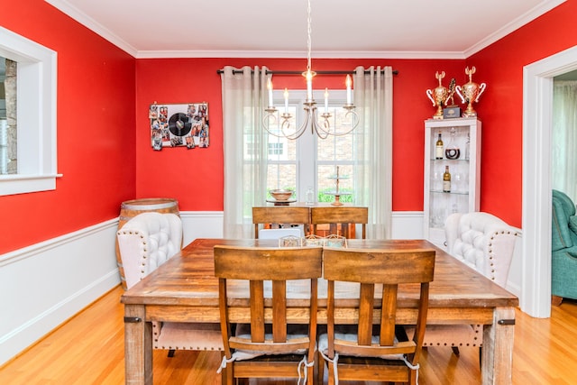 dining room featuring wood finished floors, a chandelier, and crown molding