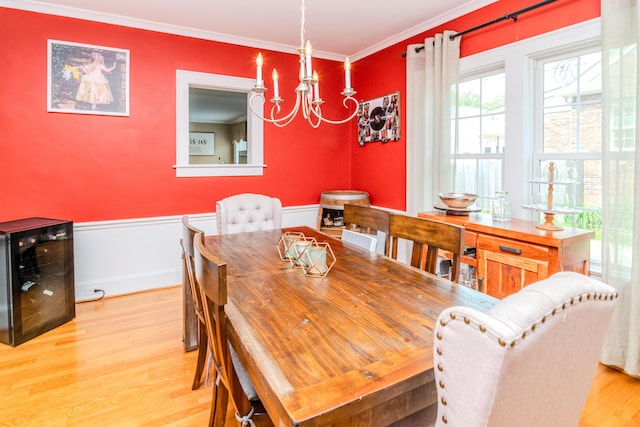 dining room with beverage cooler, a chandelier, wood finished floors, a wainscoted wall, and ornamental molding