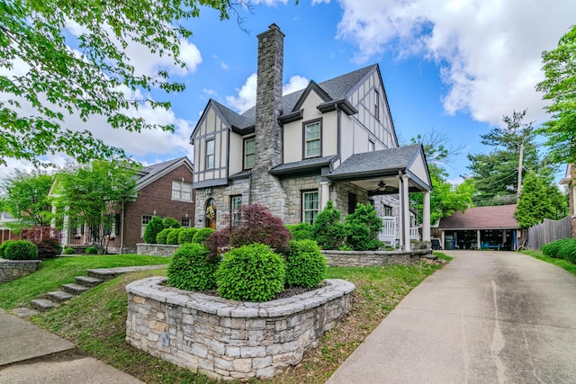 view of front of home featuring stucco siding, stone siding, a chimney, ceiling fan, and a shingled roof