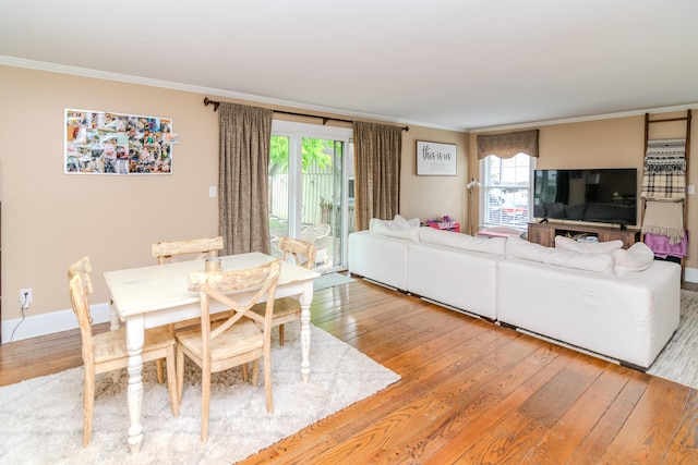 living room featuring ornamental molding, light wood-style flooring, healthy amount of natural light, and baseboards