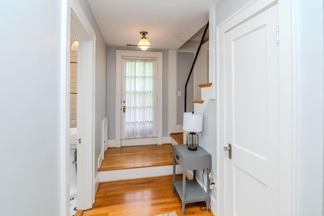 doorway featuring light wood-style flooring, stairway, and baseboards