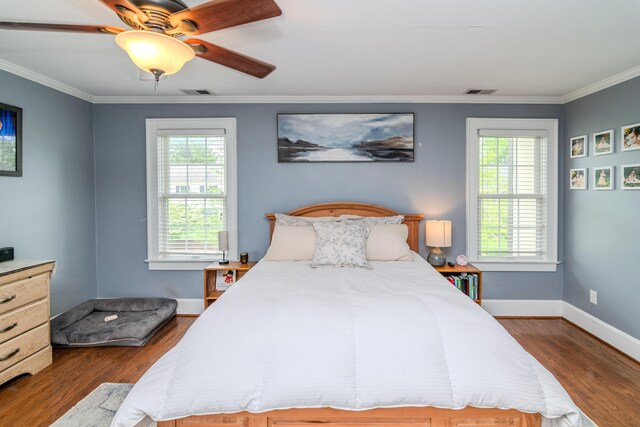 bedroom with multiple windows, dark wood finished floors, ornamental molding, and baseboards