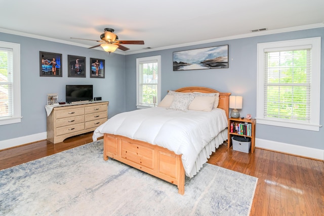 bedroom featuring crown molding, wood finished floors, baseboards, and ceiling fan