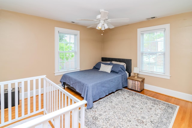 bedroom with multiple windows, baseboards, wood finished floors, and ceiling fan