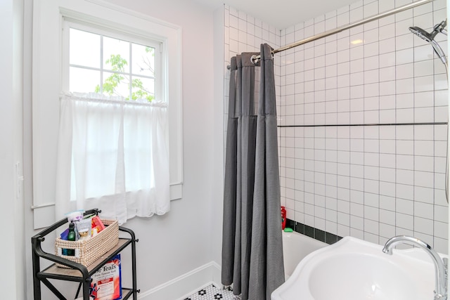 bathroom with a sink, shower / bath combo, and baseboards