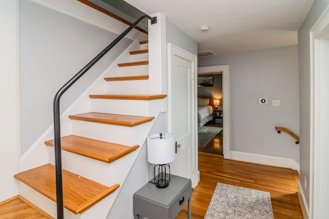 staircase featuring wood finished floors and baseboards