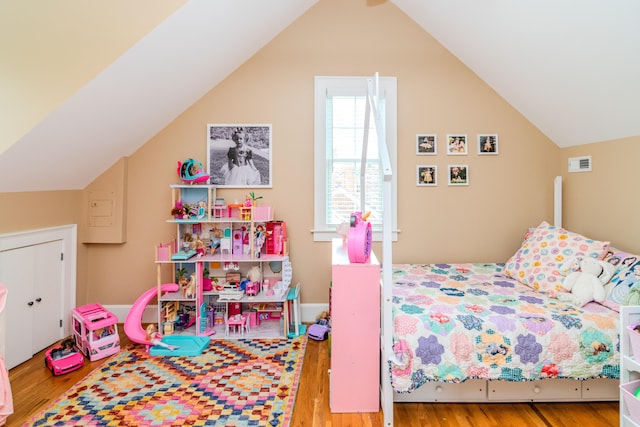 bedroom with wood finished floors and lofted ceiling