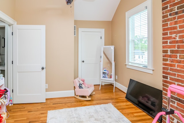 rec room with healthy amount of natural light, wood finished floors, baseboards, and lofted ceiling