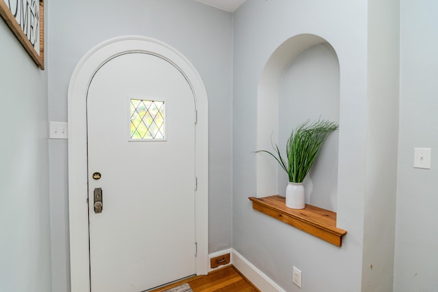 entrance foyer featuring wood finished floors, arched walkways, and baseboards