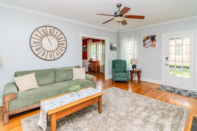 living room with wood finished floors, crown molding, a ceiling fan, and baseboards