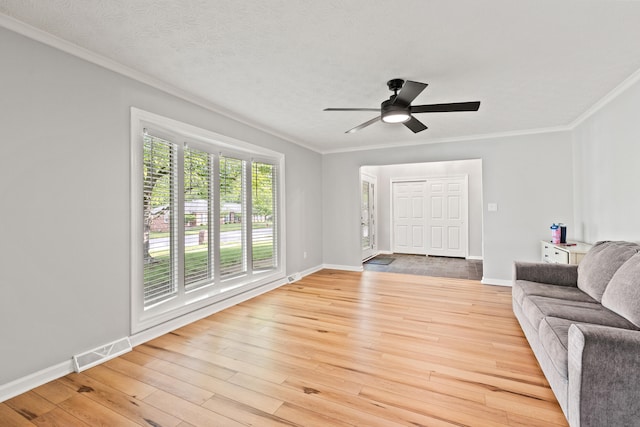 living room with light wood finished floors, ceiling fan, crown molding, and baseboards