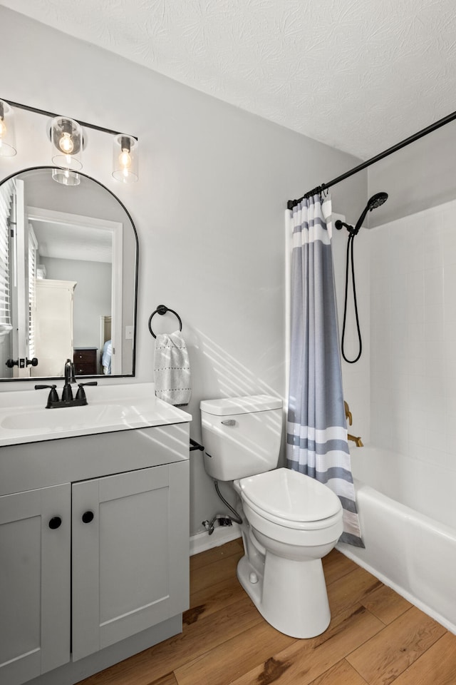 full bath with toilet, wood finished floors, vanity, shower / bathtub combination with curtain, and a textured ceiling