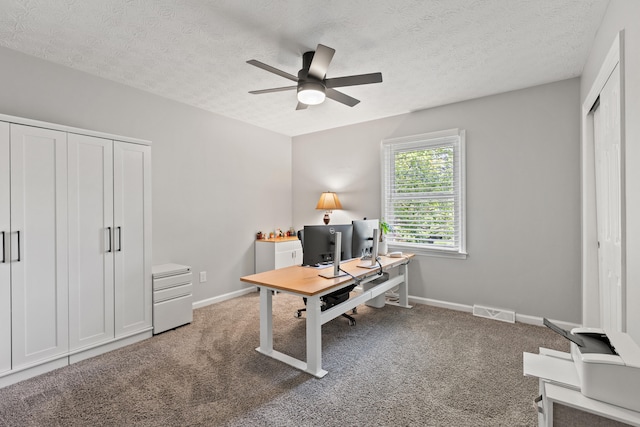 carpeted office space with a ceiling fan, baseboards, and a textured ceiling