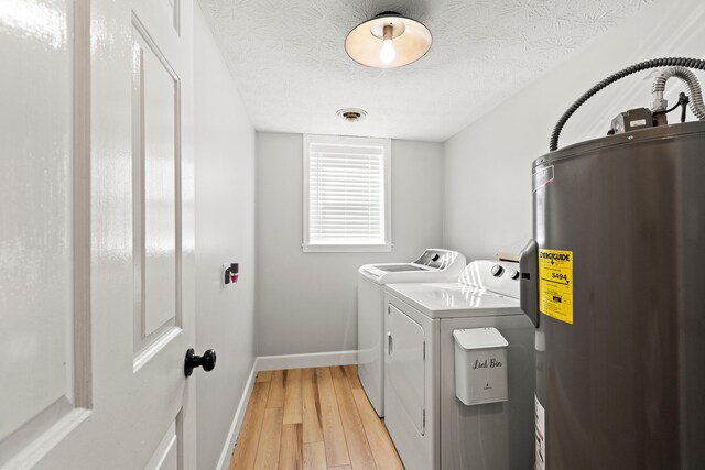 laundry room featuring water heater, independent washer and dryer, baseboards, light wood-type flooring, and a textured ceiling