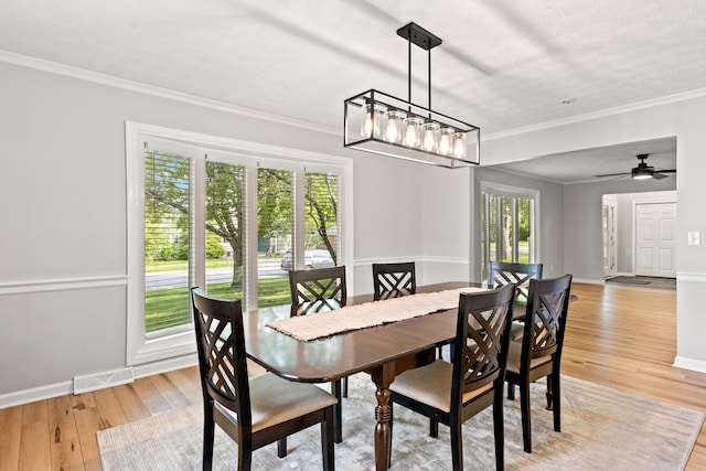 dining room featuring light wood finished floors, crown molding, baseboards, and a chandelier