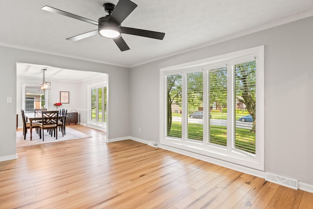 living room with light wood-type flooring, baseboards, ceiling fan, and ornamental molding