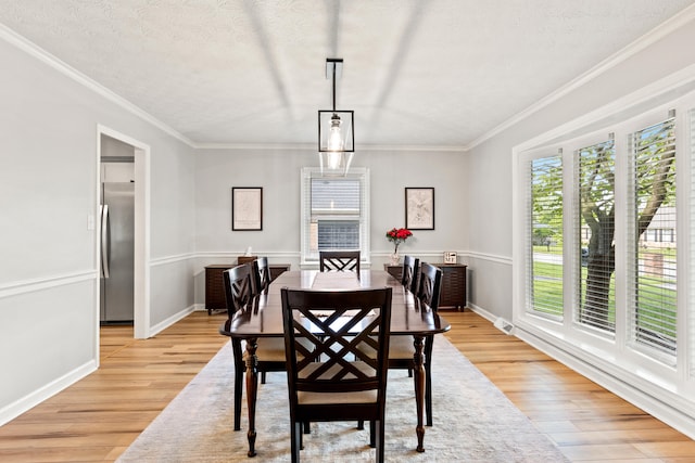 dining space featuring light wood-type flooring, crown molding, and baseboards