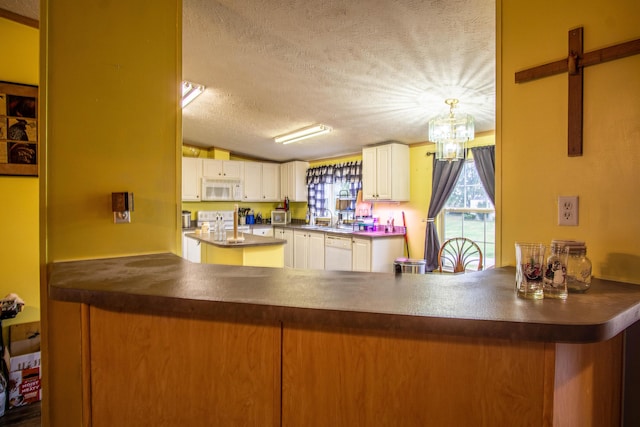 787 Wise Owl Rd, Keavy, KY 40737 - kitchen with a peninsula, dark countertops, a textured ceiling, white appliances, and a chandelier