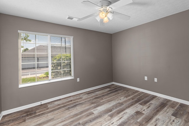 spare room featuring wood finished floors, healthy amount of natural light, and baseboards