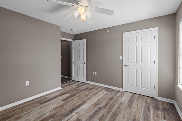 unfurnished bedroom featuring wood finished floors, baseboards, and ceiling fan