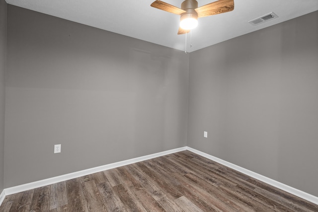 empty room featuring dark wood finished floors, a ceiling fan, and baseboards