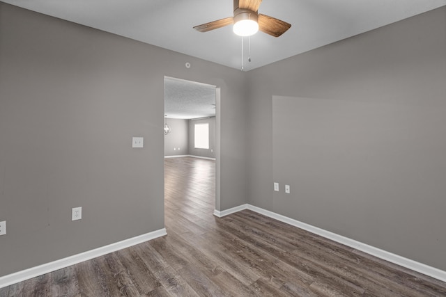 spare room with ceiling fan, baseboards, and dark wood-style flooring
