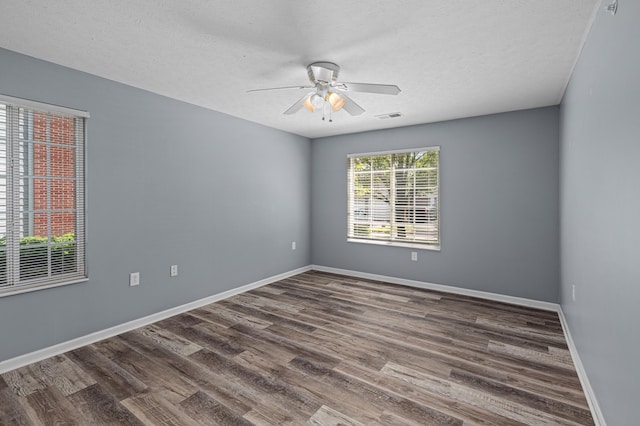 spare room featuring a ceiling fan, dark wood-style flooring, baseboards, and a textured ceiling