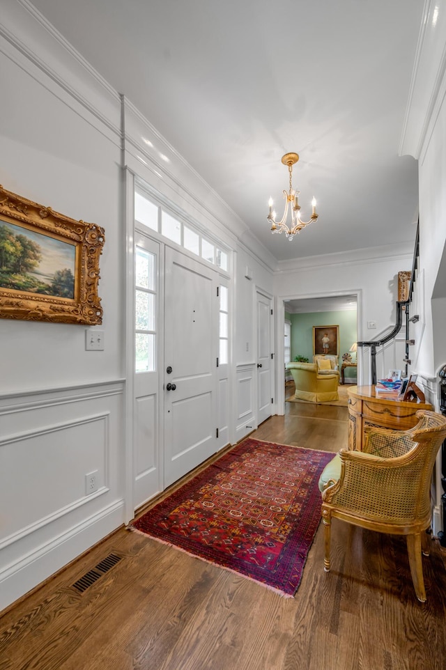 1775 Mooreland Dr, Lexington, KY 40502 - foyer featuring ornamental molding, a chandelier, wood finished floors, a decorative wall, and a wainscoted wall