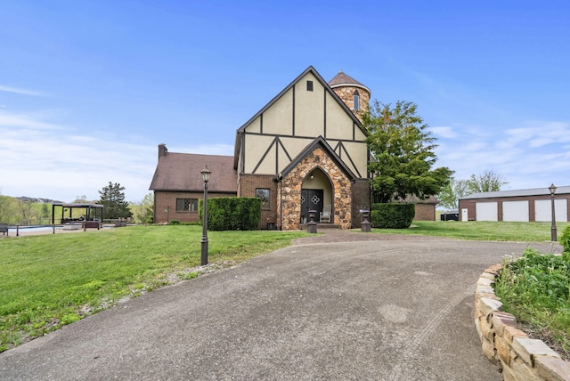129 Adams Ln, Richmond, KY 40475 - tudor-style house featuring driveway, a garage, stone siding, stucco siding, and a front yard