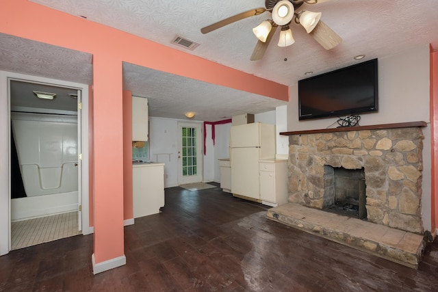 17590 New Columbus Rd, Corinth, KY 41010 - unfurnished living room with a textured ceiling, dark wood-type flooring, visible vents, ceiling fan, and a stone fireplace