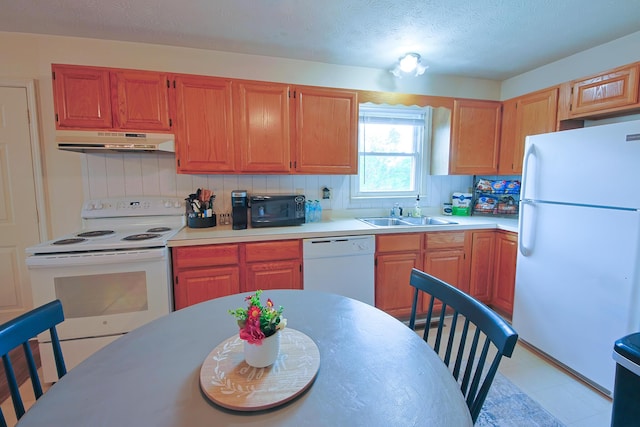 kitchen featuring a sink, white appliances, under cabinet range hood, decorative backsplash, and light countertops