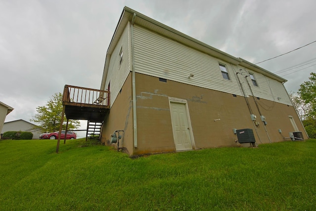 back of house featuring a lawn, a wooden deck, and central air condition unit