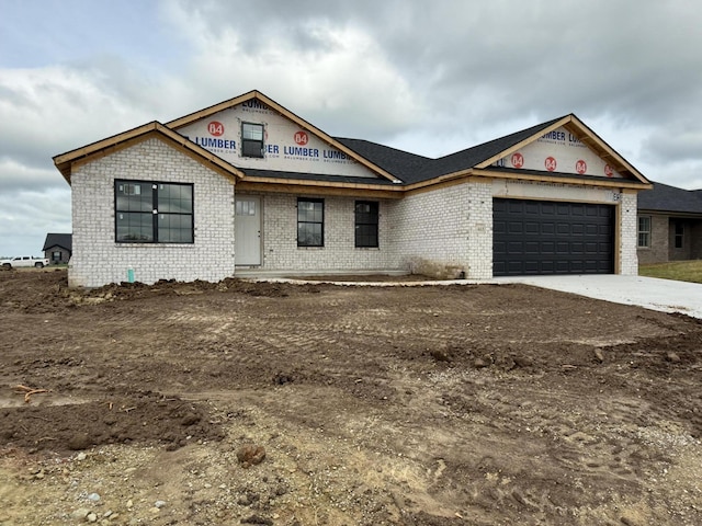 property in mid-construction with a garage, brick siding, and driveway