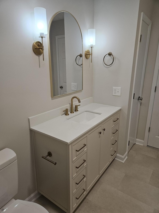 half bathroom with toilet, vanity, and baseboards