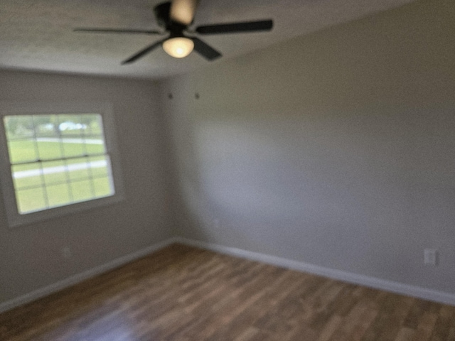 empty room with wood finished floors, baseboards, and a ceiling fan